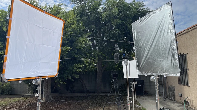 Five Key Lessons to Learn Before Buying Film and Photography Gear Two large fabric reflectors with orange and silver frames mounted on stands in a residential outdoor space