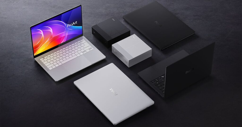 Asus’ RTX Spark-Powered ProArt PCs Promise Pro Performance for Creators A group of laptops and desktop mini PCs in black and silver colors are arranged on a dark surface; one laptop screen displays a colorful abstract wallpaper.