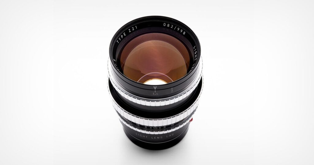 Light Lens Lab 75mm f/1.5 ‘Z21’ Prime Has An Entirely Original Optical Design A camera lens with a black body and silver focus rings is shown from above on a white background. The glass elements reflect light, and text around the lens edge reads “TYPE Z1 LIGHT LENS LAB.”.