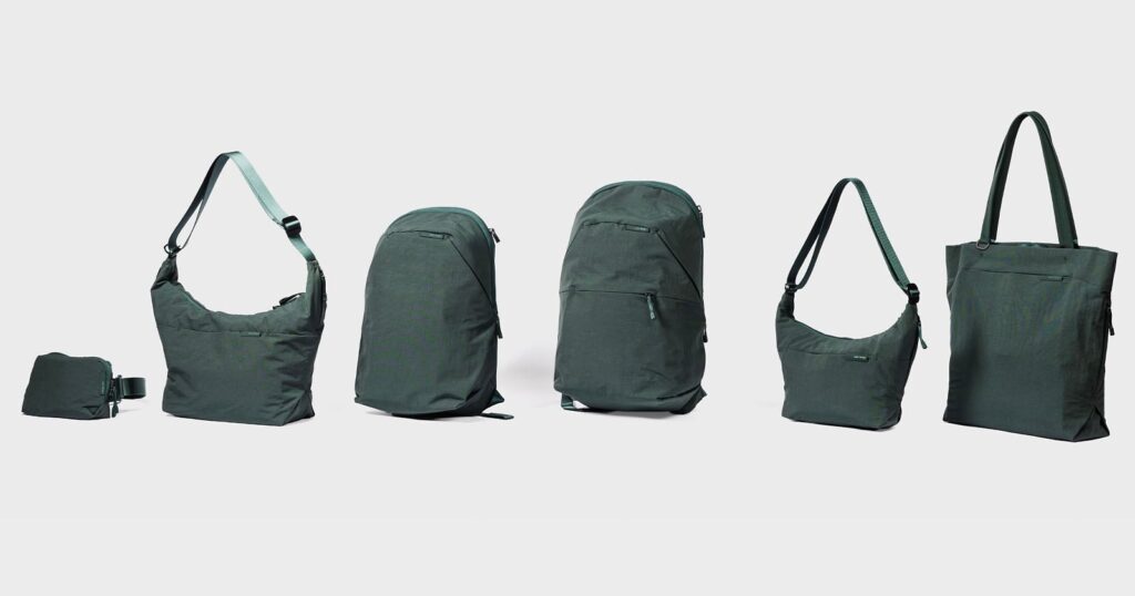 A lineup of six dark green bags, including a small waist pack, two shoulder bags, two backpacks, and a tote bag, arranged against a light gray background.