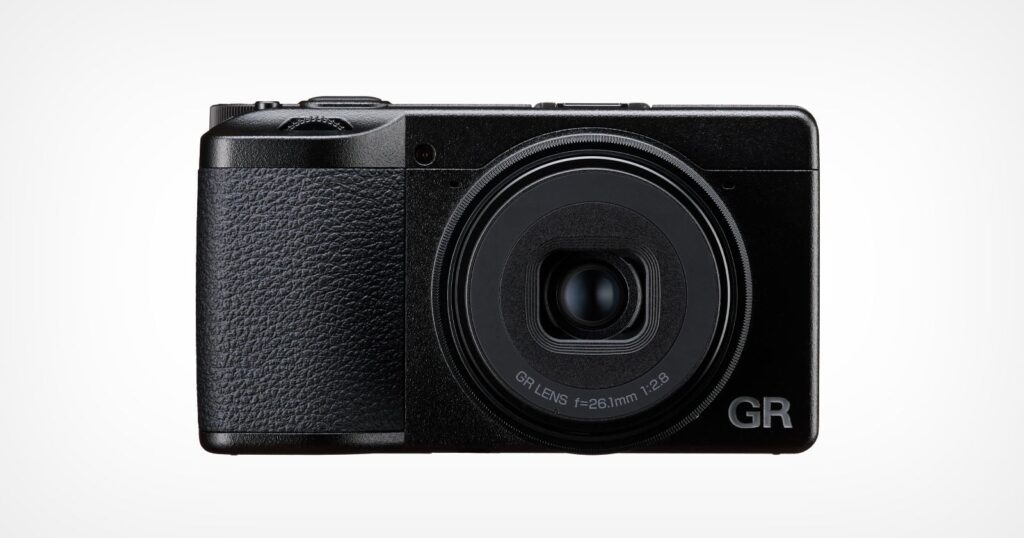 A front-facing view of a black compact digital camera with a textured grip on the left side and a lens labeled "GR LENS f=26.1mm 1:2.8" on the right.