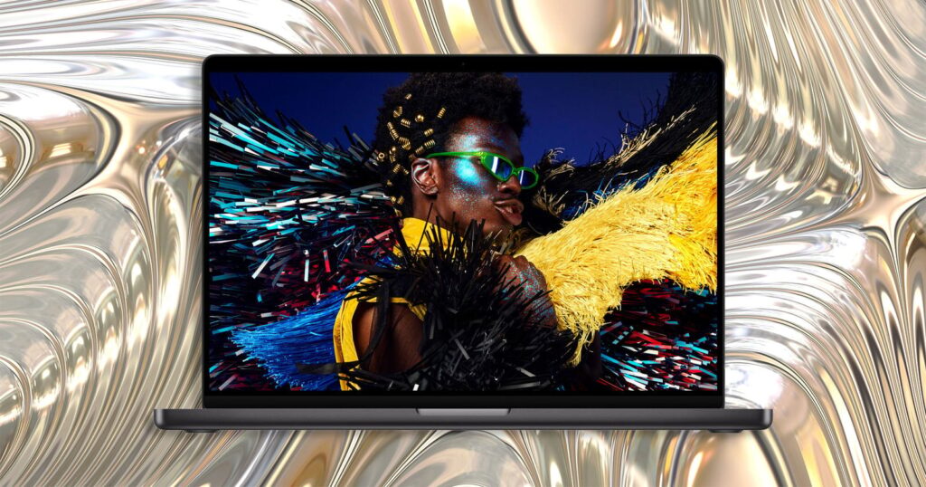 A laptop screen displays a portrait of a person with glittery makeup and bright green sunglasses against a metallic, liquid-like background.