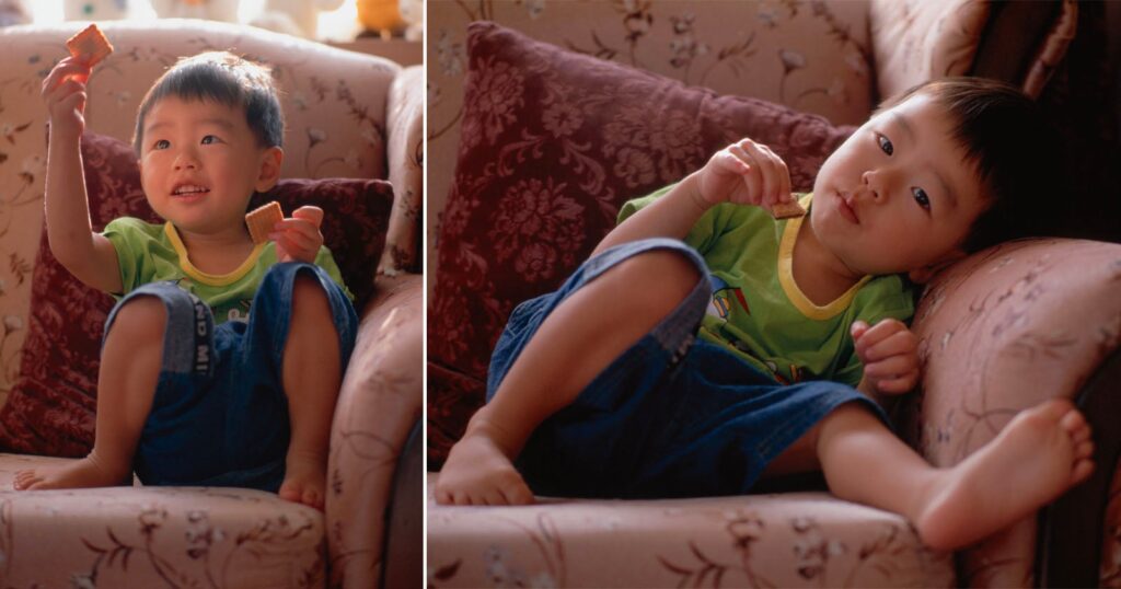 10 Great Vintage Lenses for Portrait Photography A young child in a green shirt and blue shorts sits on a patterned couch, holding and eating a small square cracker in two different poses.