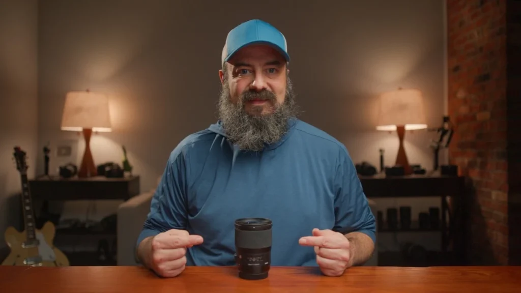 28mm: The Sweet Spot for Home Video Bearded man in a blue cap and blue shirt pointing at a black camera lens standing on a wooden table