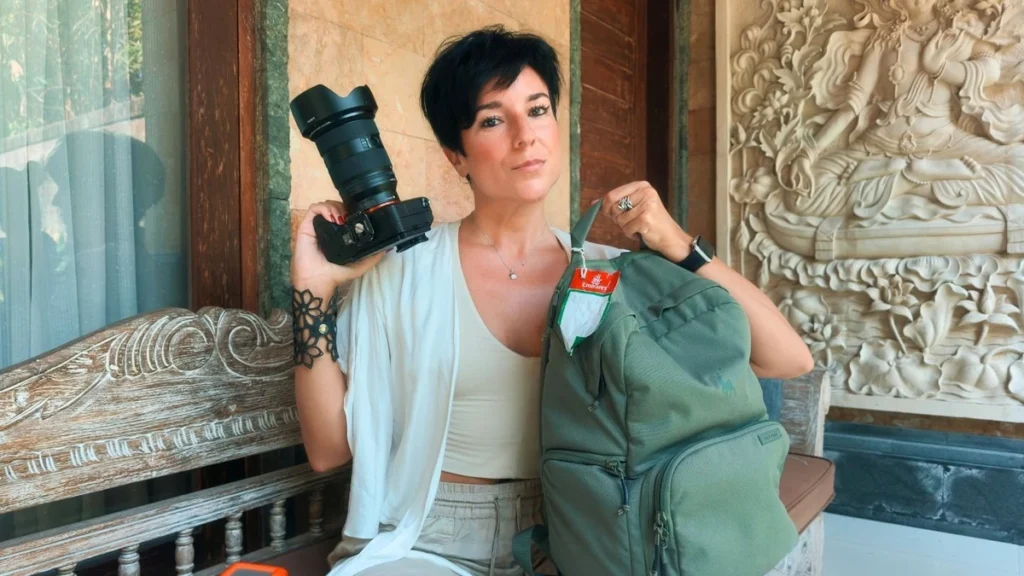 Photographer holding professional DSLR camera and green backpack in ornate interior space