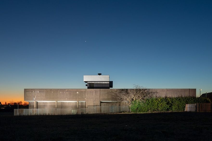 A forgotten stash of government-issue soap, a riveted blast door and a stairwell lit by a single bulb: these photos reveal the inside of a secret Cold War bunker The Nottingham War Rooms at dusk, its flat-roofed brutalist block and raised lookout structure silhouetted against a deep blue sky fading to orange on the horizon, with a single bright star overhead.