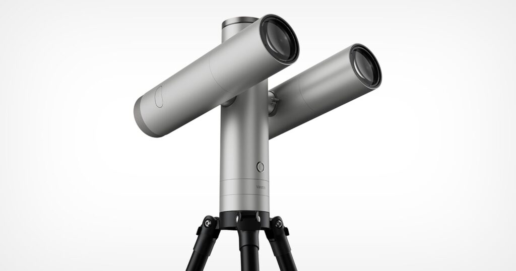The Vaonis Atlas Is a Smart Telescope Crossed With a DSLR A silver, dual-lens telescope mounted on a black tripod against a white background, with the word "vaonis" printed on the central pillar.